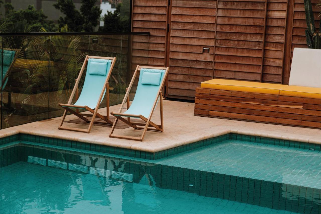 The Click Clack Hotel Medellín Exteriér fotografie A pair of deck chairs by a pool
